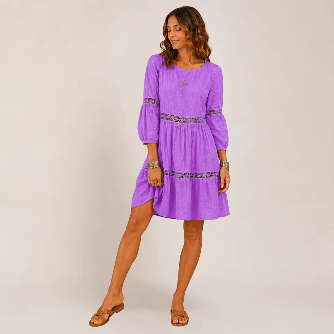 Model wearing a 3/4 sleeve sundress with a flowing tiered silhouette on a plain background.