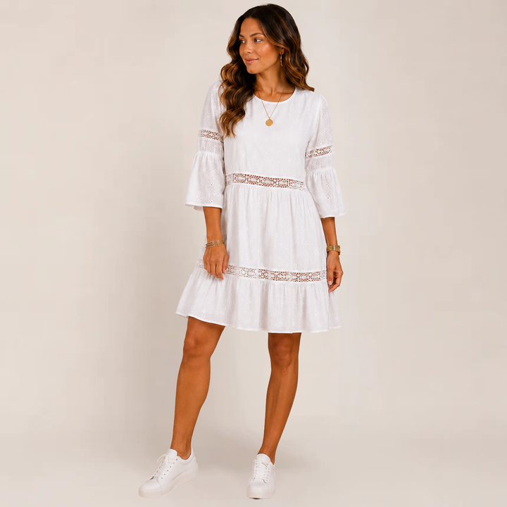 Female model wearing a flowy tiered sundress with 3/4 sleeves on a plain background.