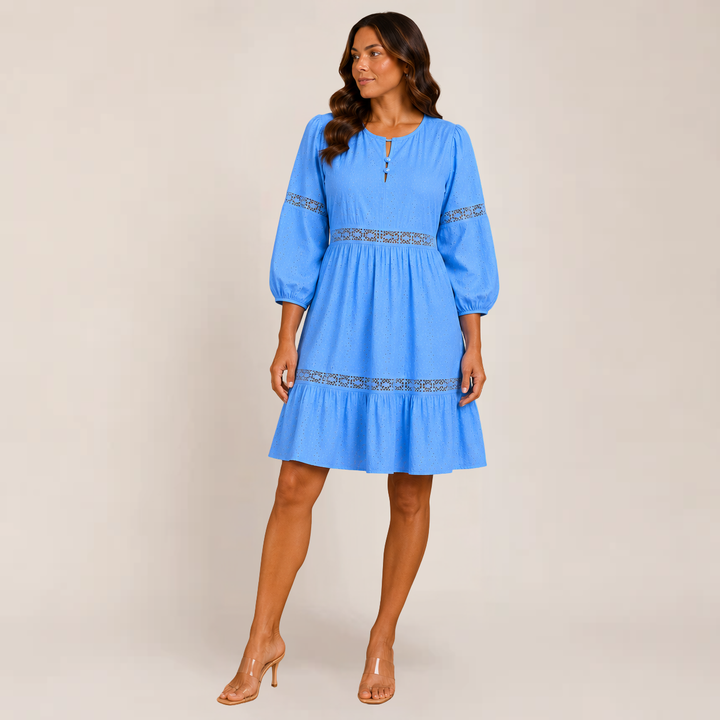Woman in a relaxed tiered summer dress with soft movement on a plain background.