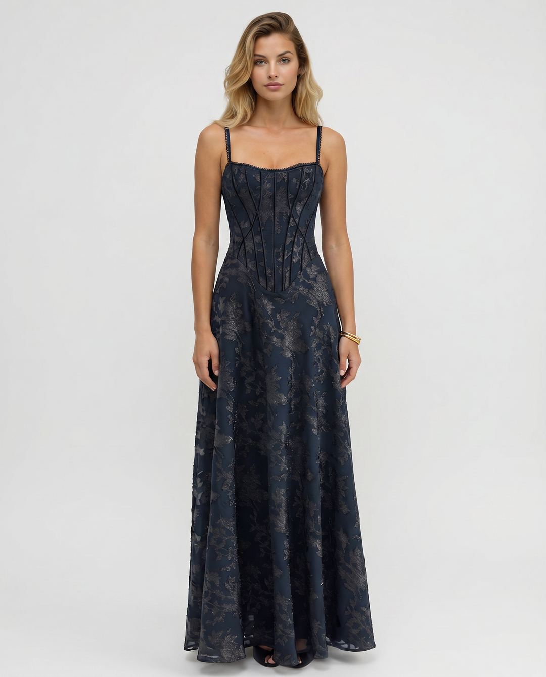 Woman wearing a maxi dress with a structured bodice and flowing skirt against a plain background.