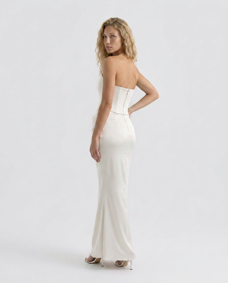 Female in a strapless maxi dress designed with a structured bodice and flowing silhouette on a plain background.