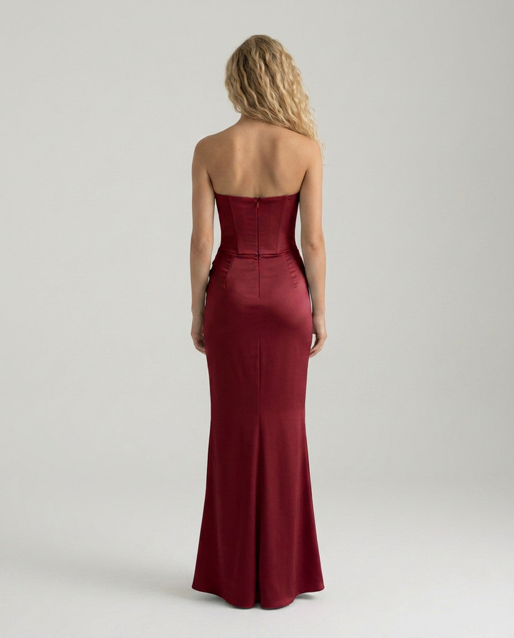 Female in a long dress featuring soft draping and a flattering silhouette on a plain background.