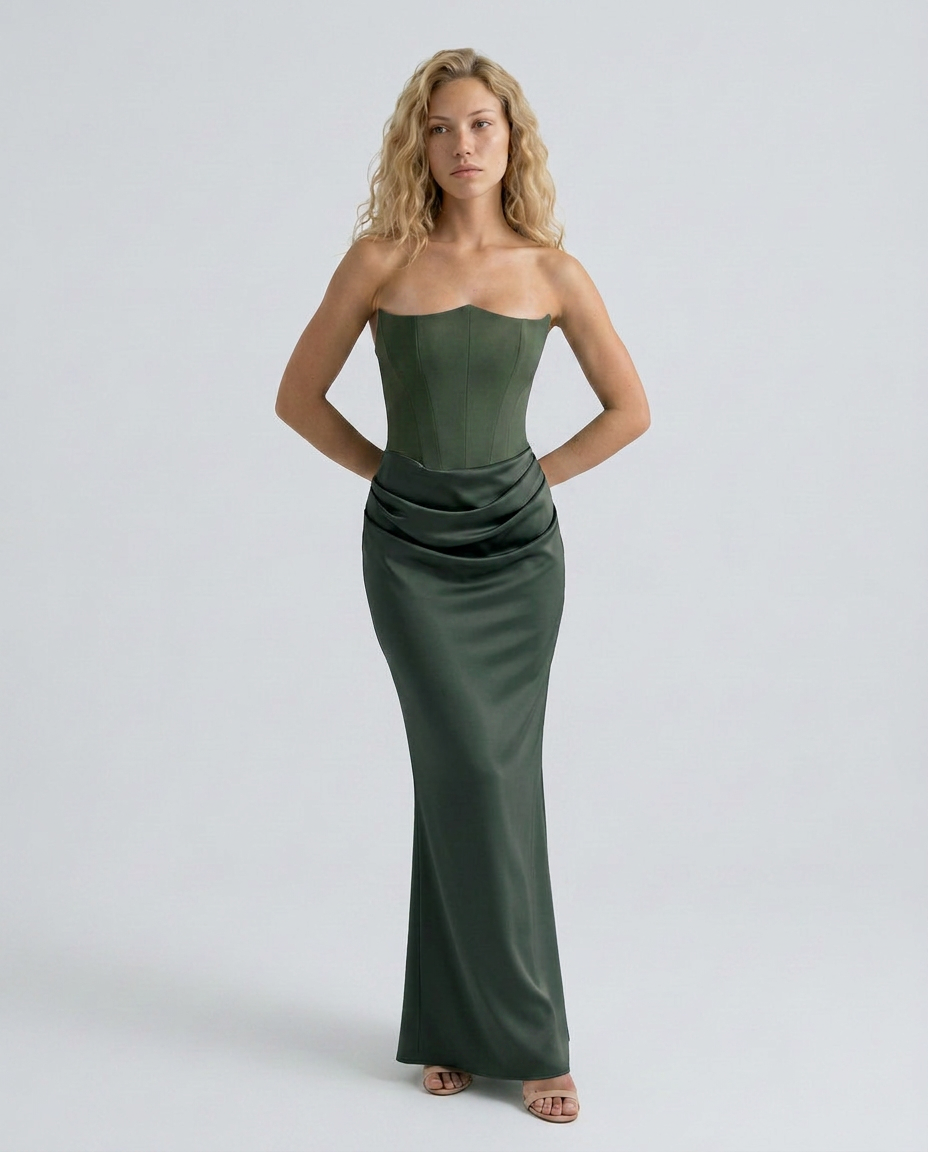 Woman in a formal maxi dress with elegant drape detailing and smooth finish on a plain background.