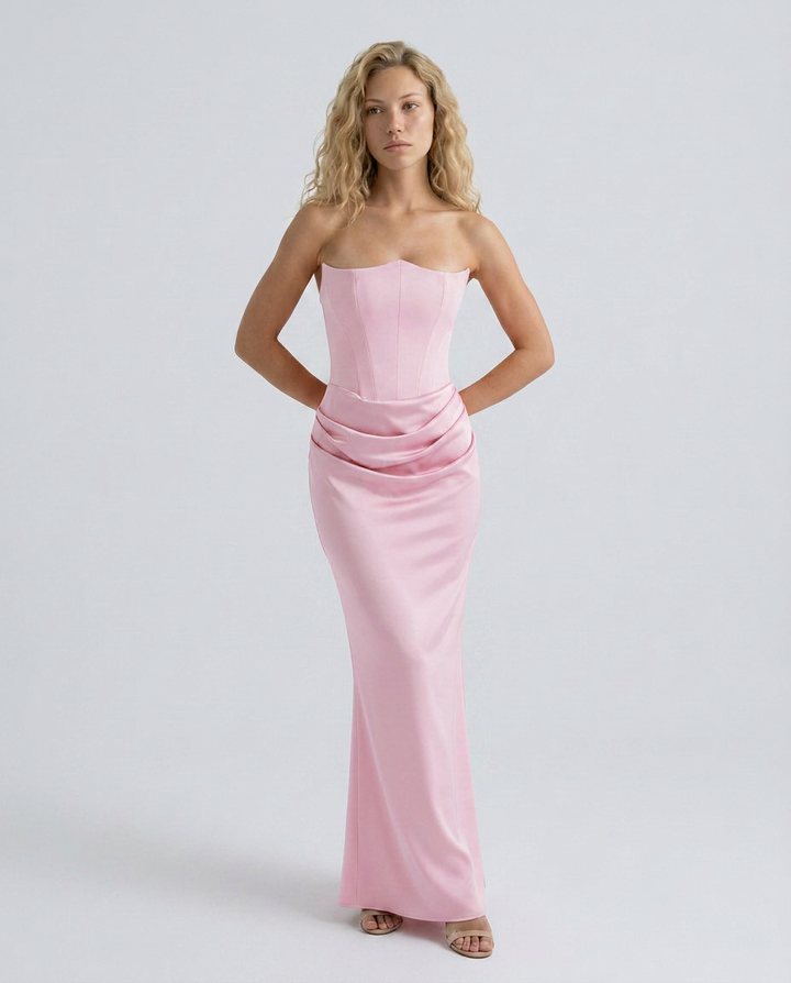 Woman wearing a strapless formal dress with a flowing skirt and defined bodice on a plain background.