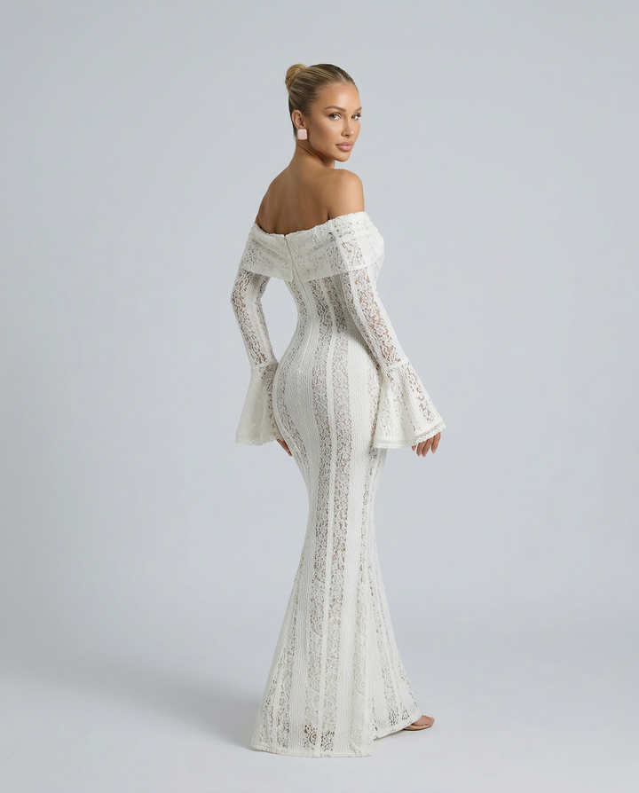 Woman in an off-shoulder floral lace dress with long sleeves on a plain background.