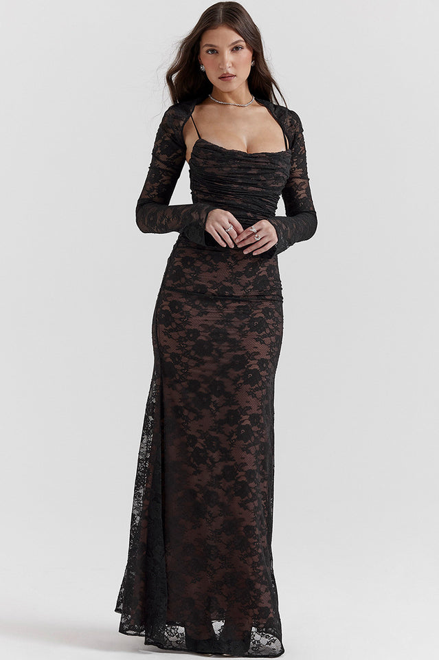 Female wearing a fitted lace maxi dress with long sheer sleeves against a plain background.