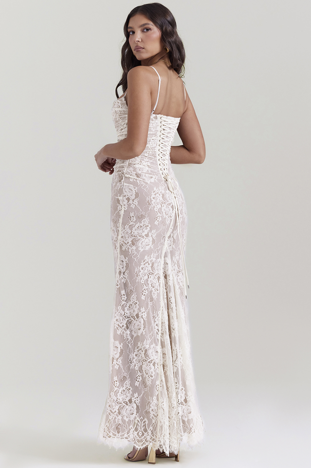 Woman in a fitted maxi dress with sheer lace sleeves on a plain background.