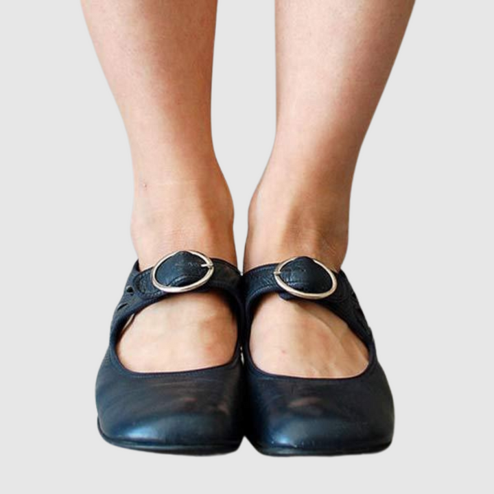 Woman wearing polished slip-on footwear on a plain background.