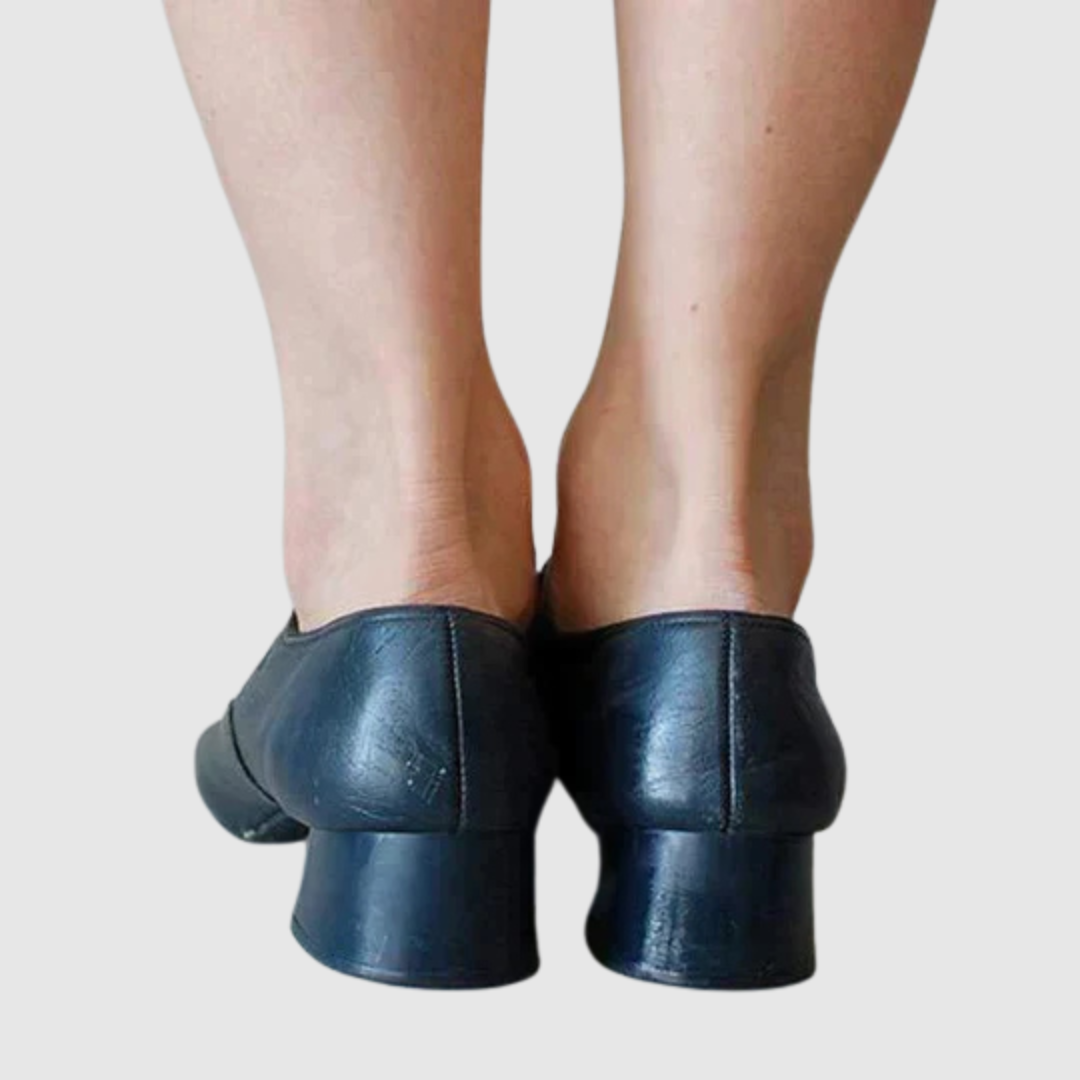 Female model displaying classic shoes with a plain background, back angle view