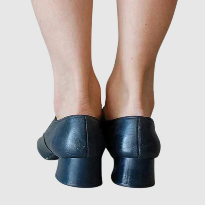 Female model displaying classic shoes with a plain background, back angle view