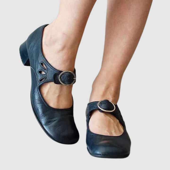 Female model standing in stylish shoes against a plain background.