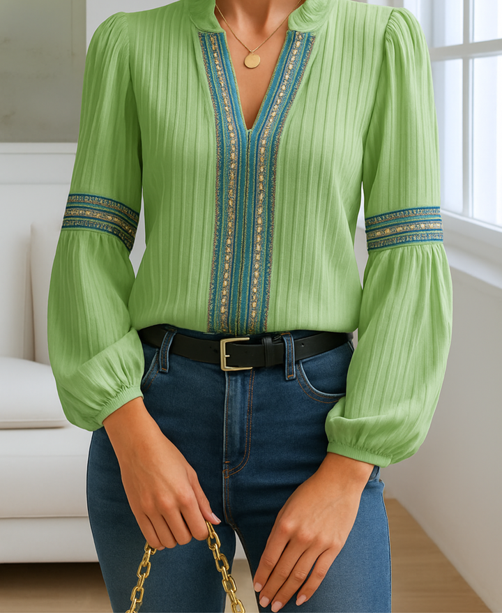 Model showcasing a women’s blouse with subtle pleating on a plain background.