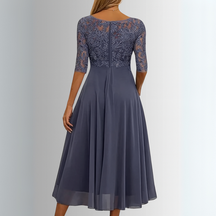 Female model wearing an occasion dress with graceful movement and detailed styling on a plain background.