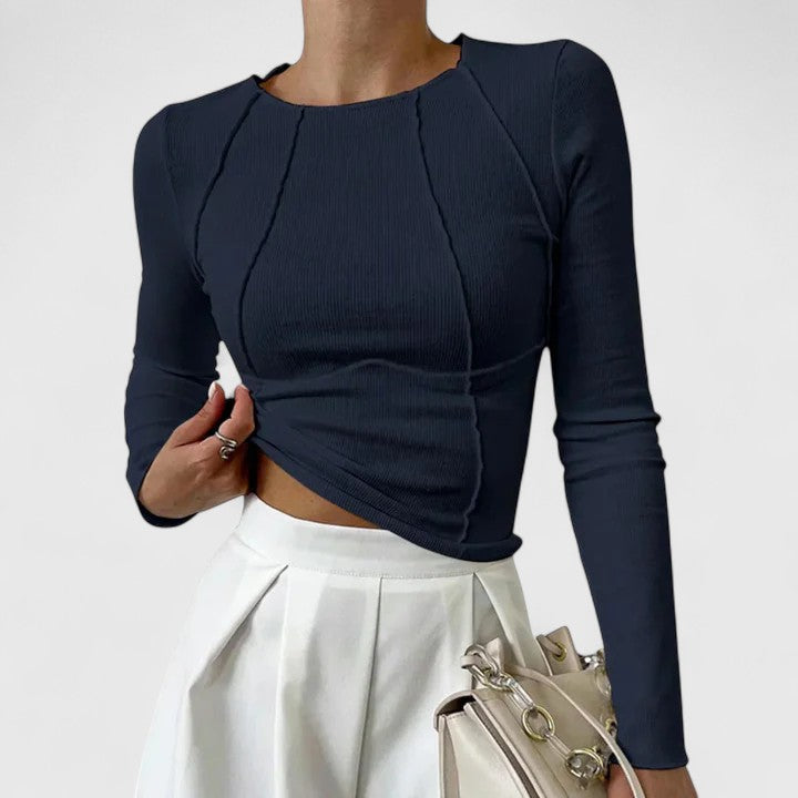 Woman styling a neat top with a simple plain background.