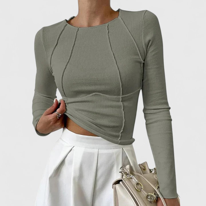 Woman in a polished casual top posed against a plain background.