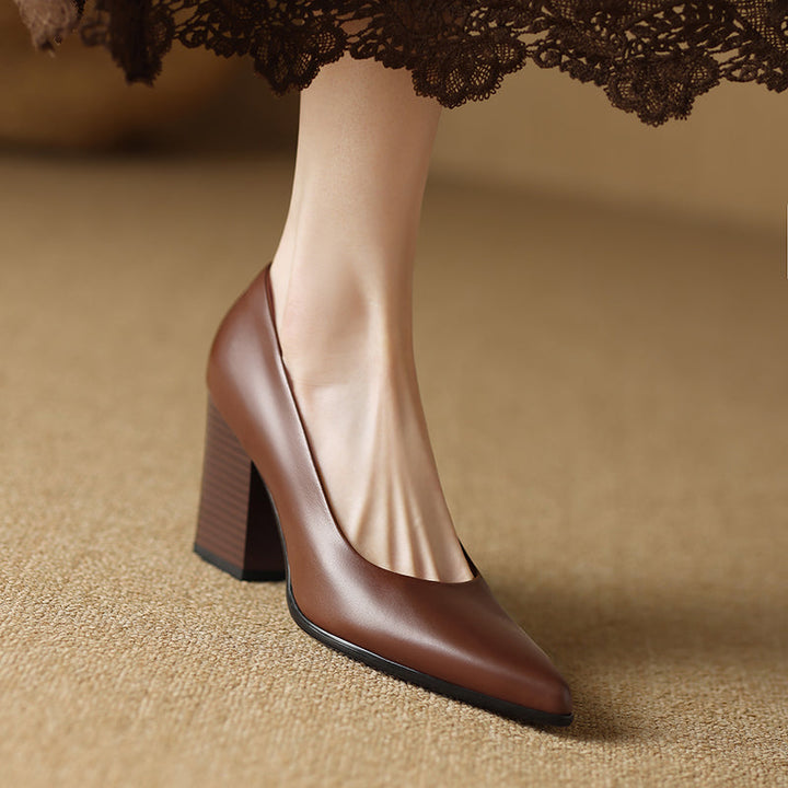 Woman styling tan block heel pumps with a clean outfit on a plain background.