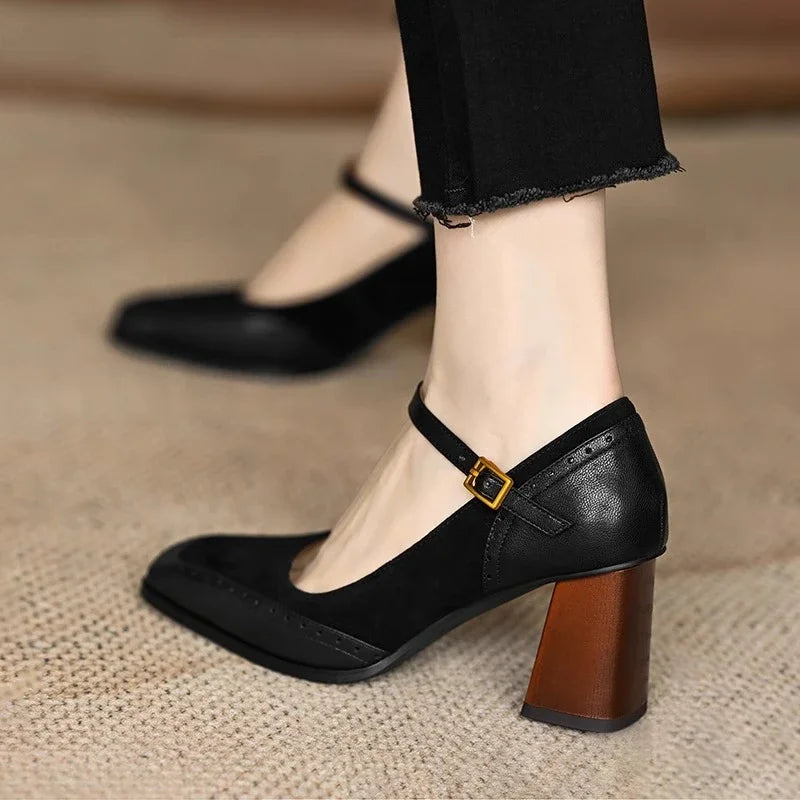 Female wearing mid-height block heel pumps with gold buckle detail on a plain background.
