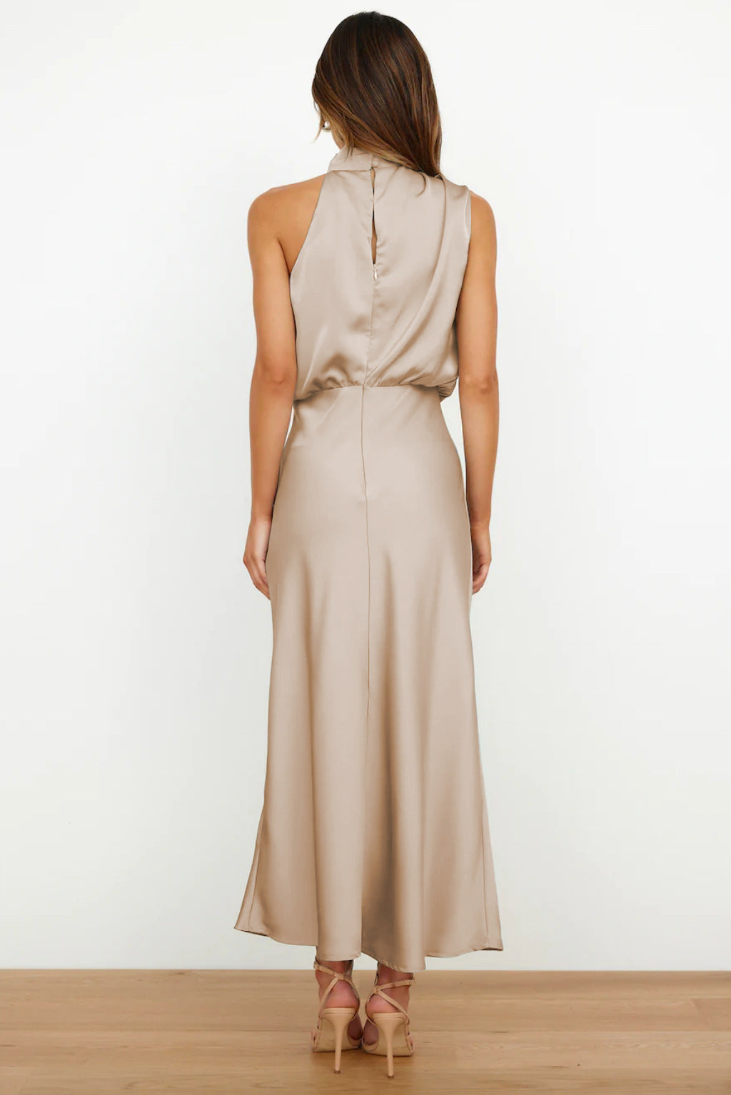 Woman standing confidently in an elegant everyday outfit with a plain background.