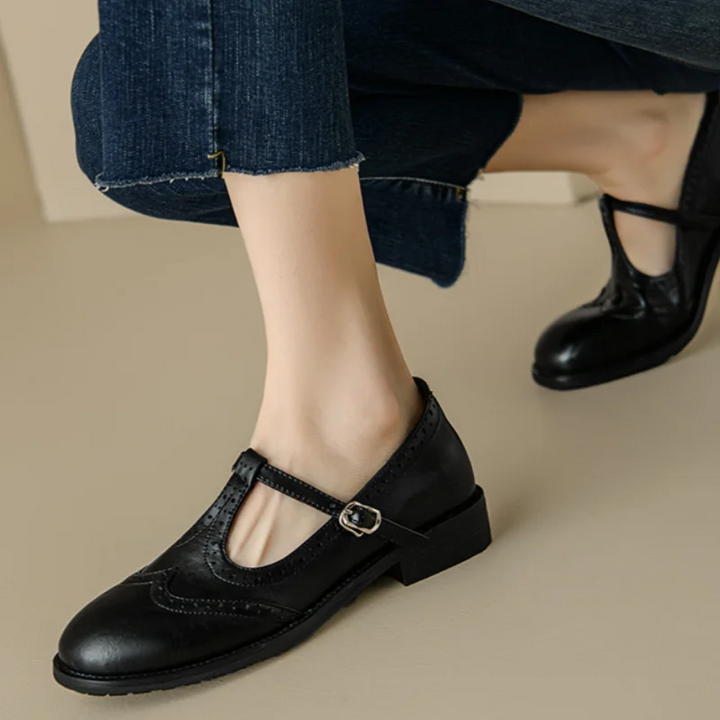 Female wearing low block heel Mary Jane shoes on a plain background.