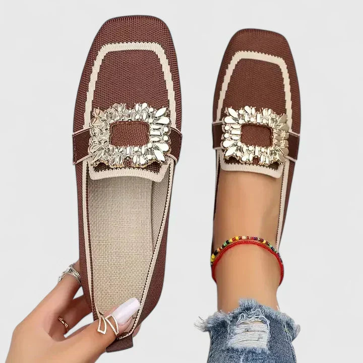 Female wearing elegant everyday loafers on a plain background.