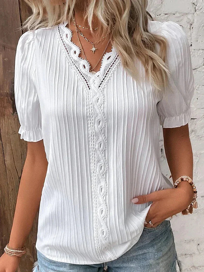 Woman wearing a lightweight blouse with short puff sleeves against a plain background.