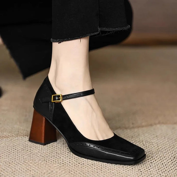 Woman showcasing retro-inspired square toe heels with ankle straps on a plain background.