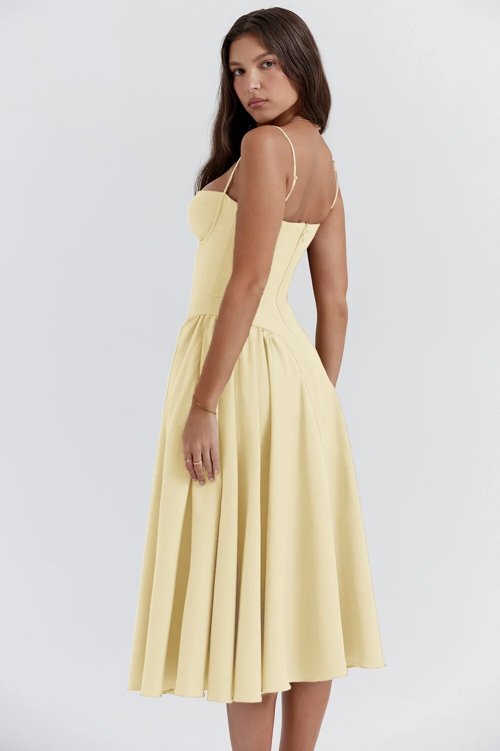 Model wearing a feminine midi dress with gentle pleats on a plain background.