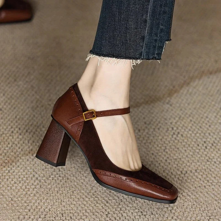 Female standing in vintage-inspired block heel pumps with brogue stitching on a plain background.