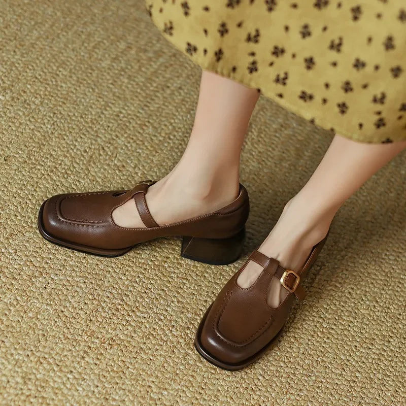 Woman standing in low block heel strap shoes with a clean square toe design.