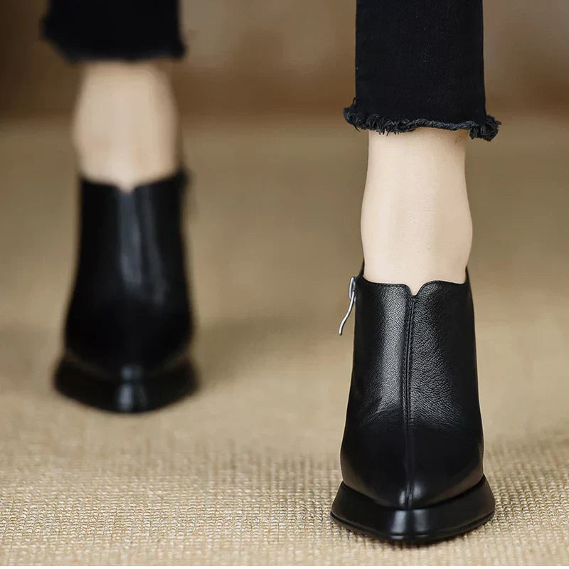 Female model styling black high heel pumps with a subtle platform on a plain background.