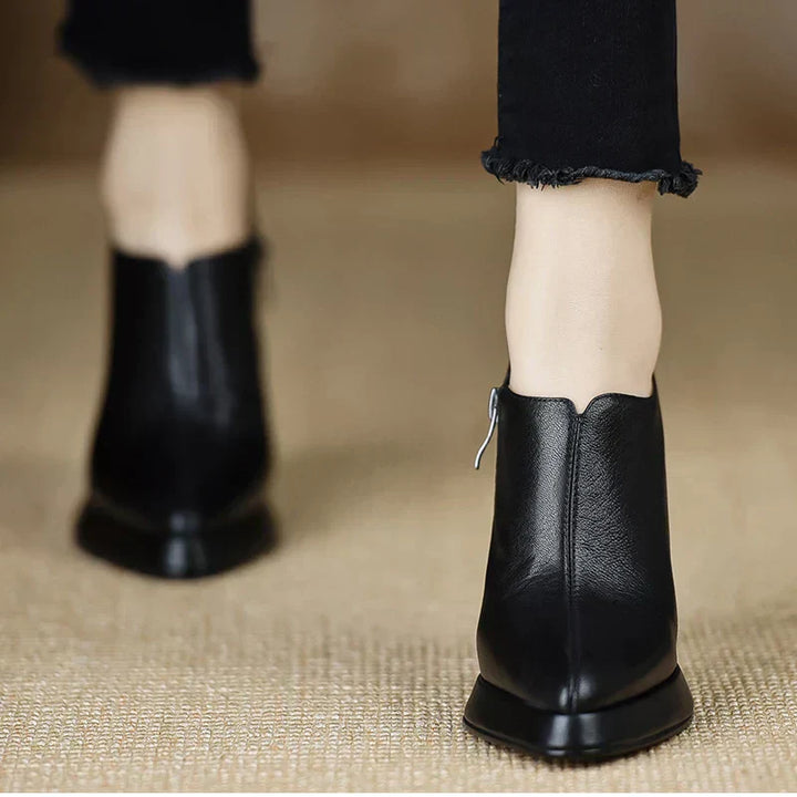 Female model styling black high heel pumps with a subtle platform on a plain background.