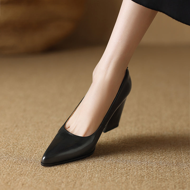 Woman standing in tan pointed toe block heels on a plain background.