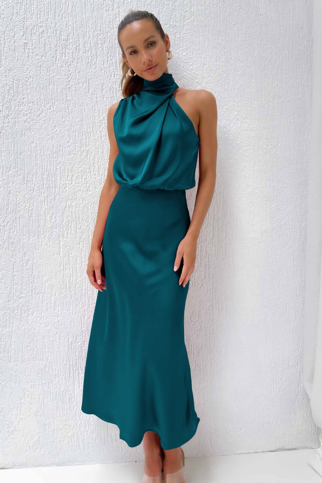 Woman displaying a modern elegant outfit with relaxed styling on a plain background.