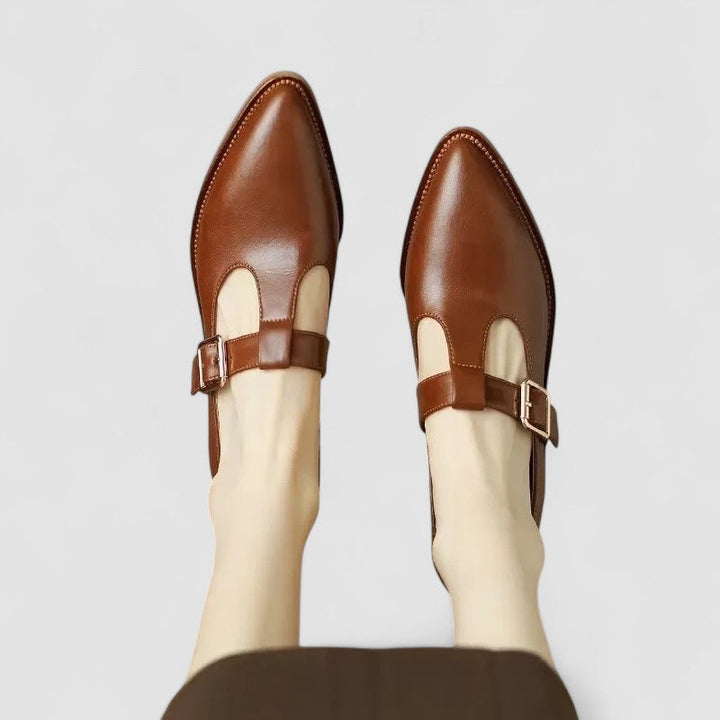 Female showcasing refined everyday shoes on a plain background.
