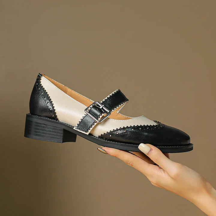 Black and cream Mary Jane shoes on a plain background.