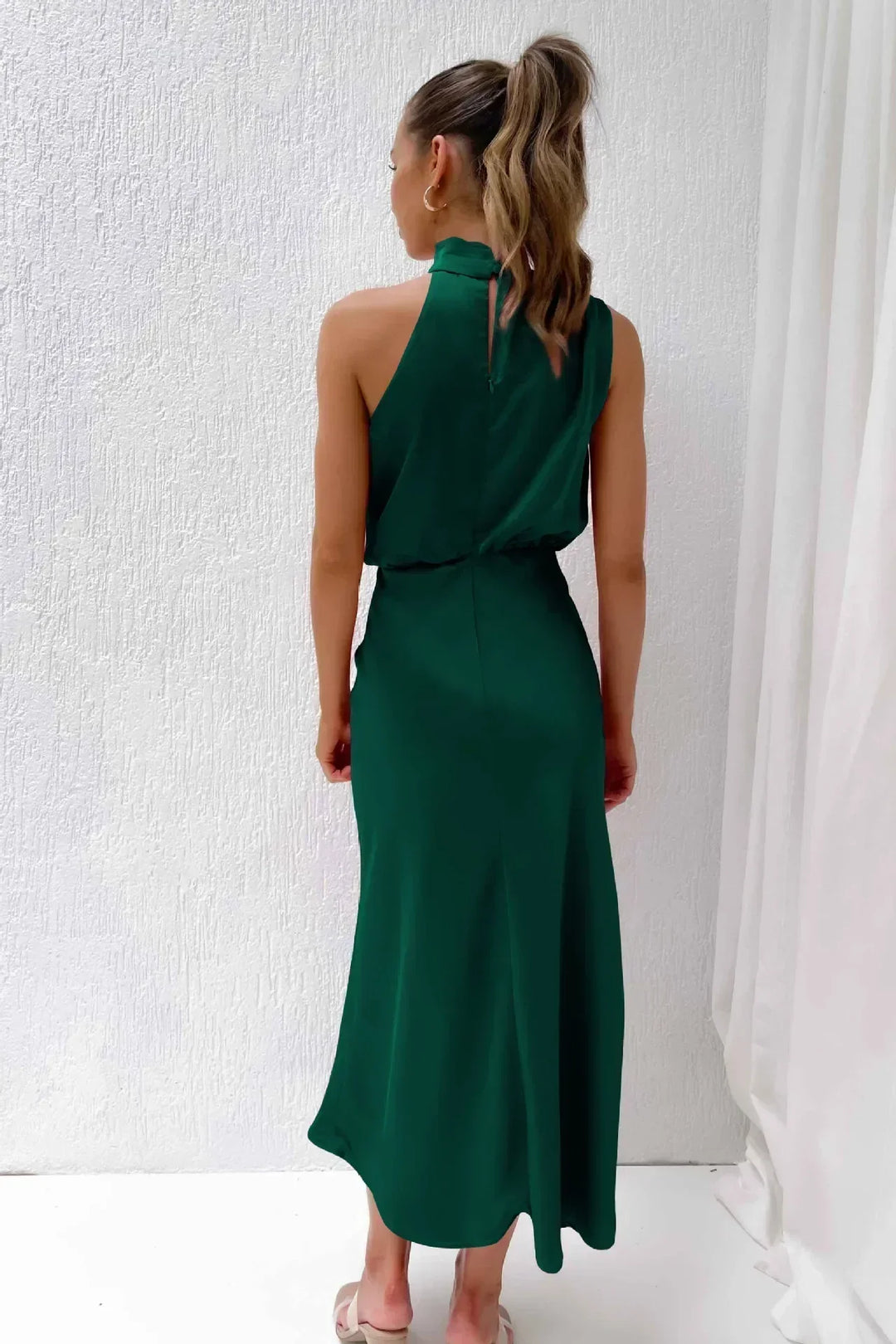 Female posing in a lightweight casual outfit against a plain studio background, back view