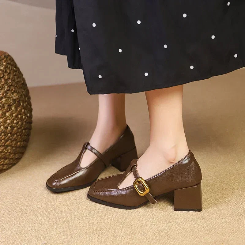 Female model wearing black block heel Mary Jane shoes on a plain background.