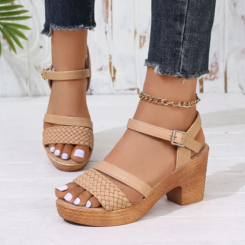 Woman wearing woven platform sandals with an ankle strap against a plain background.