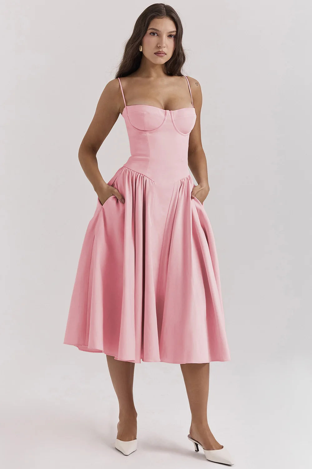 Woman posing in a breezy midi dress against a plain background.