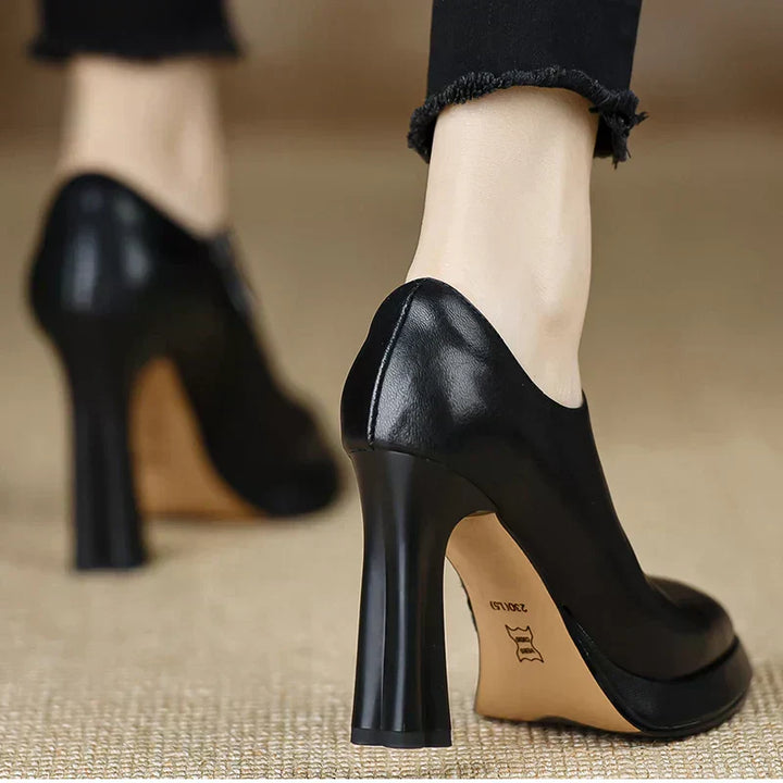 Woman wearing dark brown ankle high platform heels on a plain background.