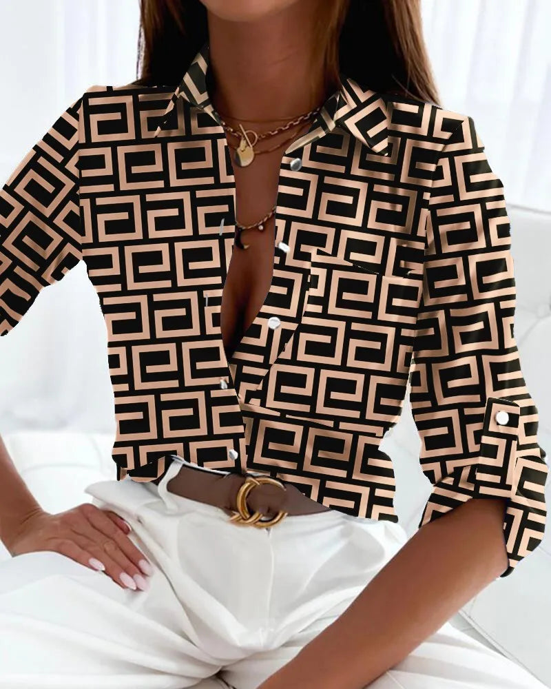  Woman in a long-sleeve blouse featuring bold geometric artwork on a plain background.