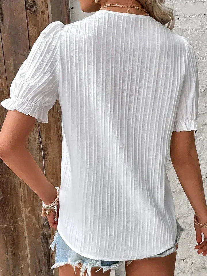  Female modelling an elegant blouse with delicate decorative detailing and a relaxed fit.
