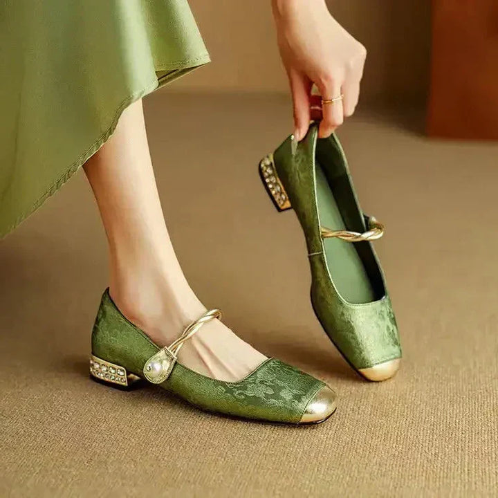 Female wearing pearl strap Mary Jane shoes with a glitter block heel on a plain background.