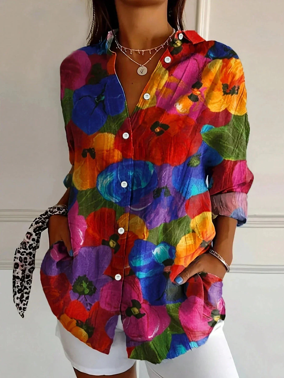 Woman wearing a lightweight floral blouse against a plain backdrop.