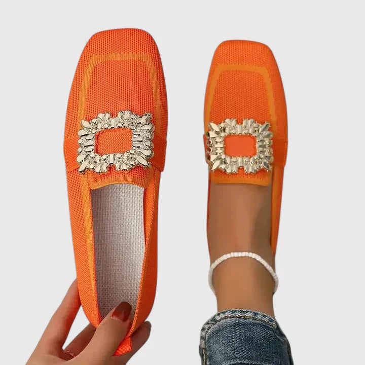 Woman modelling flexible slip-on shoes on a plain background.