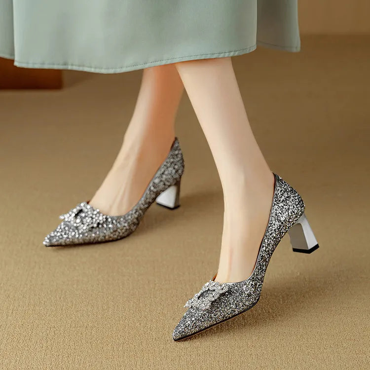 Female model posing in sparkling pointed toe pumps on a plain background.