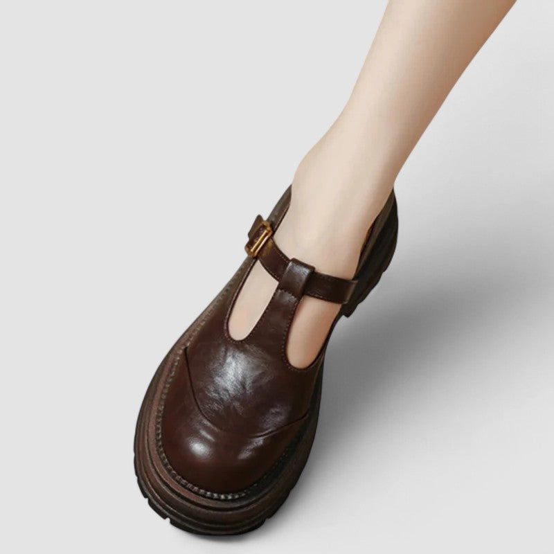 Female wearing neat strap flats against a plain background.