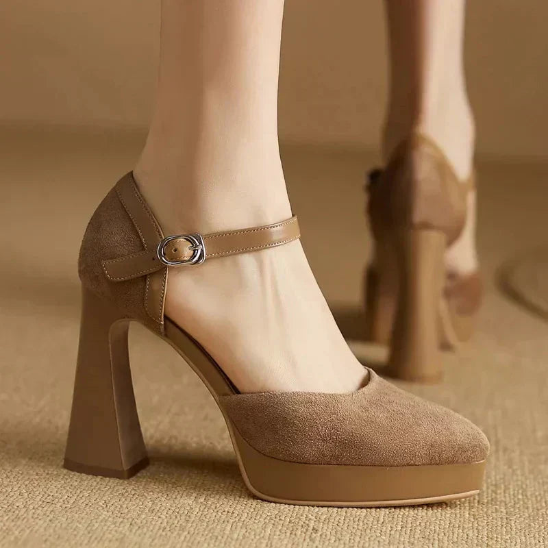 Woman wearing platform block heel pumps with ankle straps on a plain background.