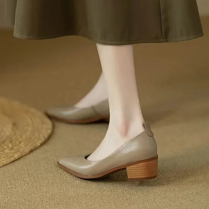 Woman showcasing stacked block heel shoes on a plain background.