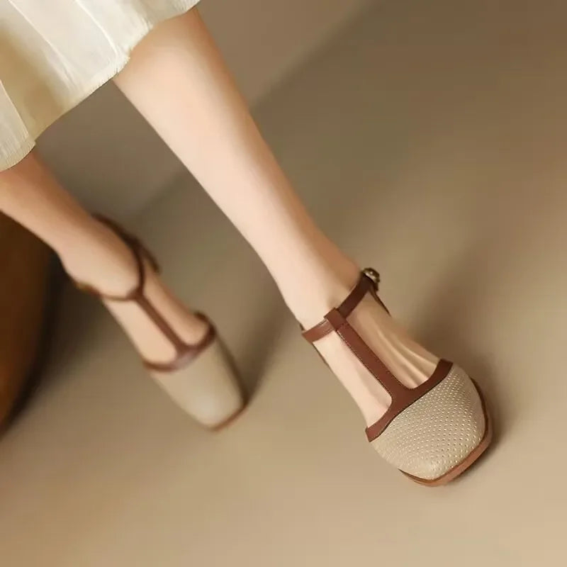Woman modelling cream block heel shoes with buckle detail on a plain background.